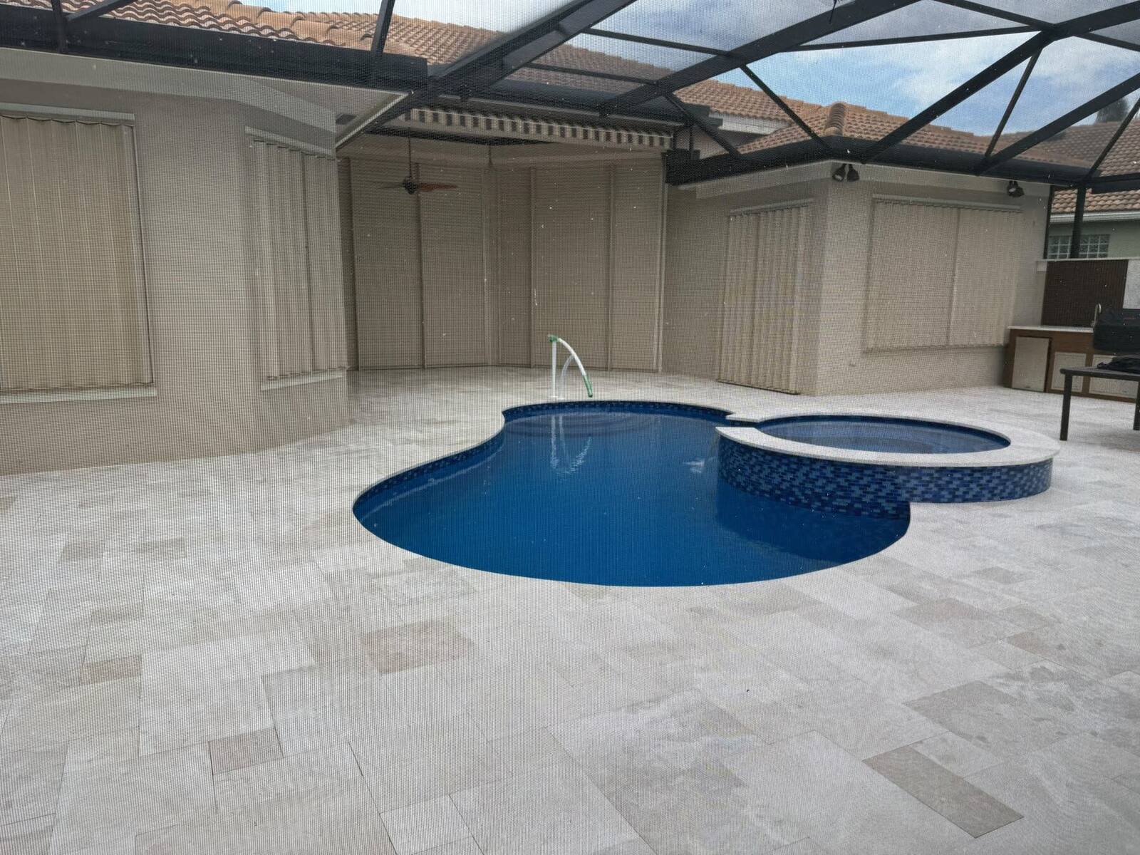 A finished custom pool with travertine deck