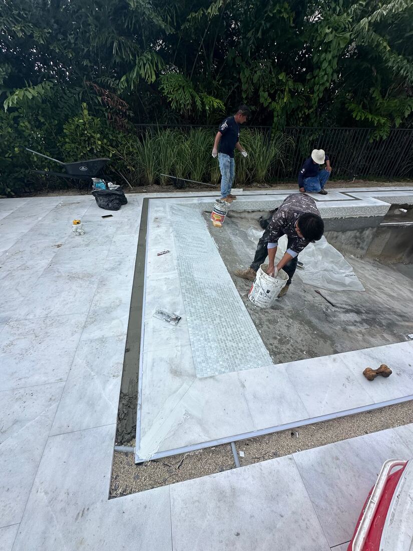Crew setting mosaic tile on the waterline